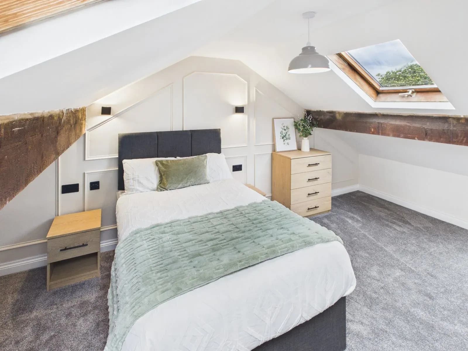 Loft-level bedroom with sloped ceiling, exposed timber beam and a rooflight at the completed Darlington HMO.